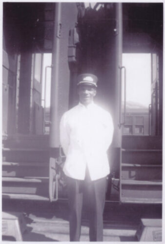Unidentified porter standing in front of train cars